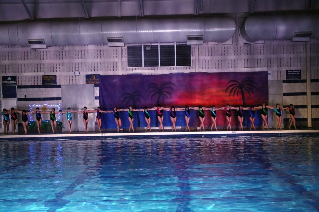 Swimmers link arms to create a line across the pool deck during their dance to the song "On Top of the World" by Imagine Dragons. Each year the participants from the girls swim team make up there own group. 